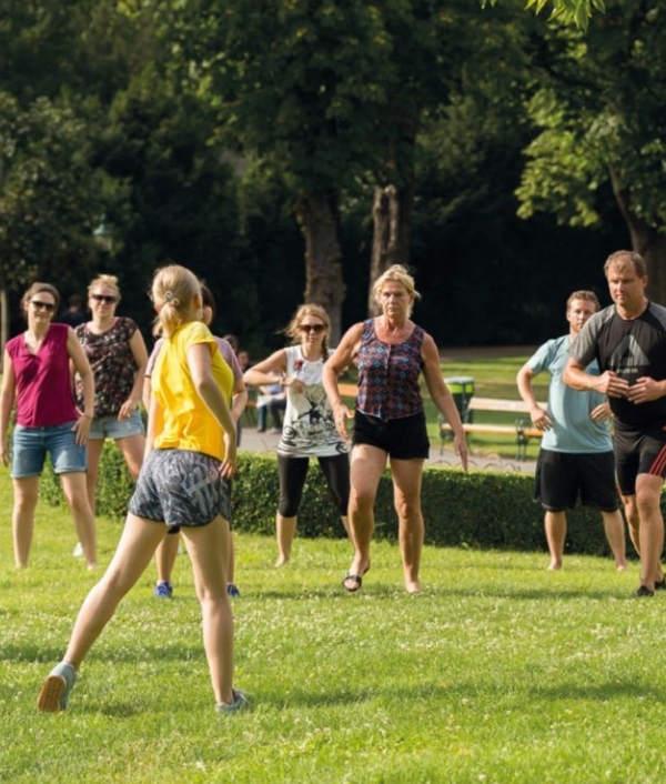 Auf dem Bild sind Teilnehmer*innen in Sportkleidung zu sehen die am Programm von Bewegt im Park teilnehmen.