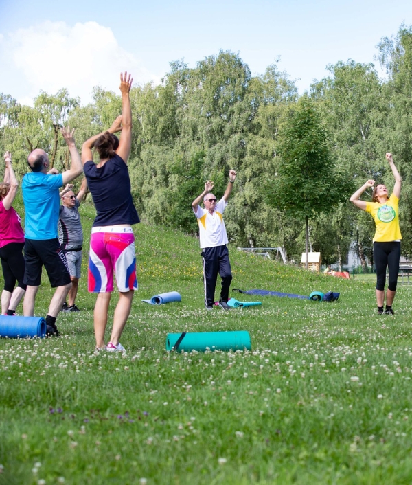 © ÖGK/wildbild Auf dem Bild sind Teilnehmer*innen in Sportkleidung zu sehen die in einem Park am Programm von Bewegt im Park teilnehmen.