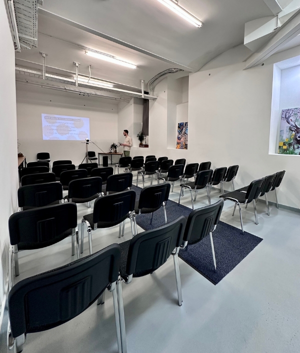 Das Bild zeigt einen Seminarraum mit schwarzen Stühlen in Theaterbestuhlung.