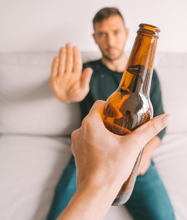 Das Bild zeigt eine Person die ihre Hand hebt und eine Flasche Alkohol ablehnt um Ihre Stimme für das Festival zu schonen.