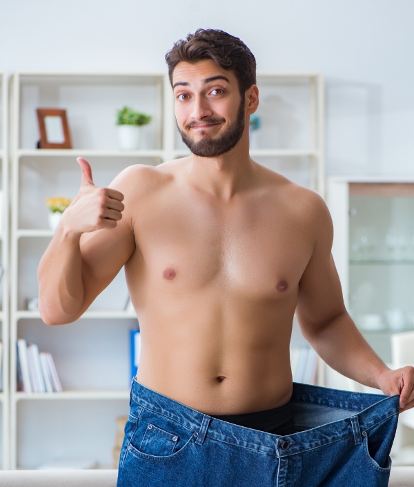 Das Bild zeigt einen muskulösen Mann in einer übergroßen Jeanshose. Er hält den Daumen hoch.