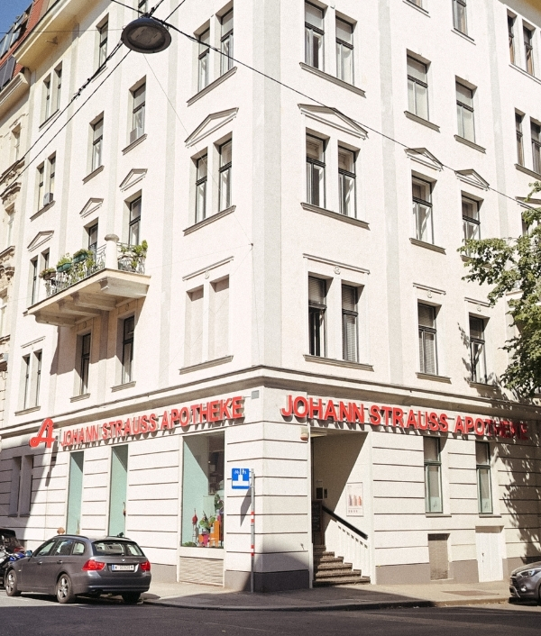 Das Bild zeigt die Johann Strauss Apotheke Wien 1040 Wieden von außen an einem sonnigen Tag.