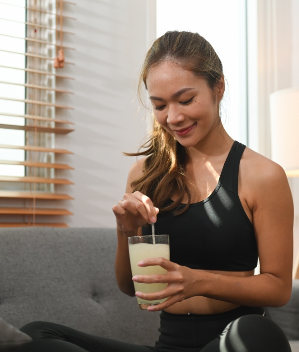 Das Bild zeigt eine Frau im Sport-Outfit mit einem Kollagen-Drink in der Hand.