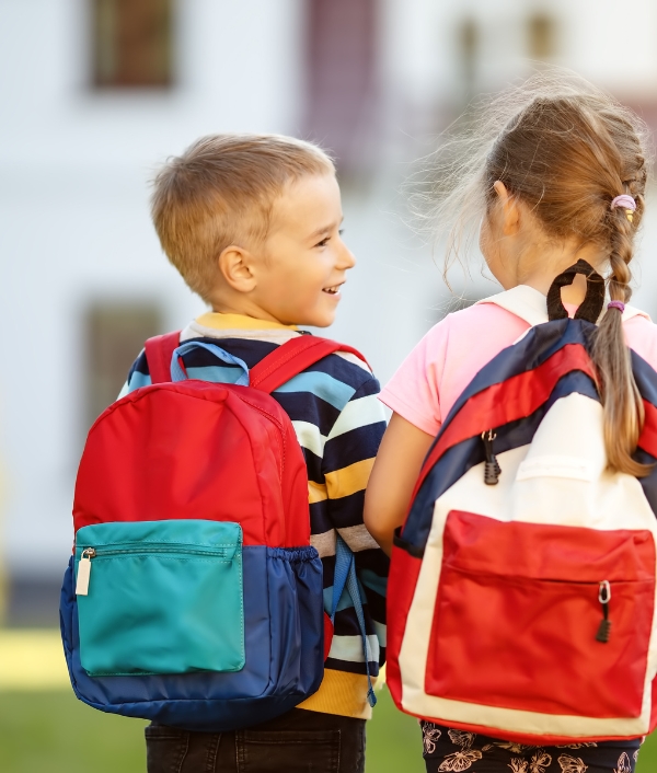 Das Bild zeigt einen Jungen und ein Mädchen mit Rucksack. Sie sind gut ausgestattet mit einem Notfall-Set für Kinder.